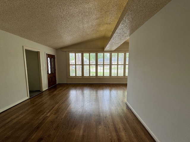 empty room with a textured ceiling, dark wood-type flooring, and vaulted ceiling