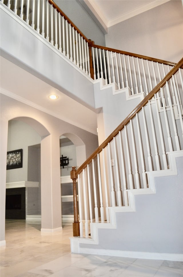 staircase featuring crown molding and a towering ceiling