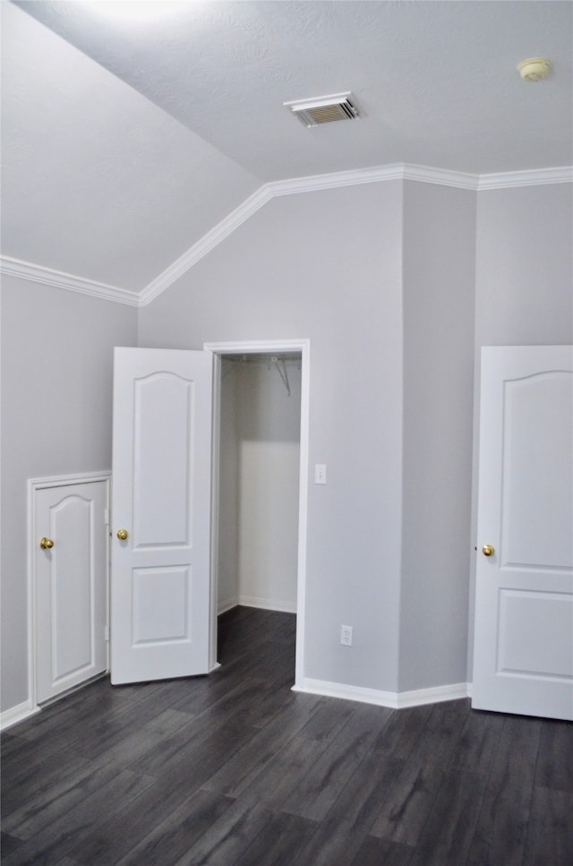 spare room with vaulted ceiling, crown molding, and dark hardwood / wood-style flooring