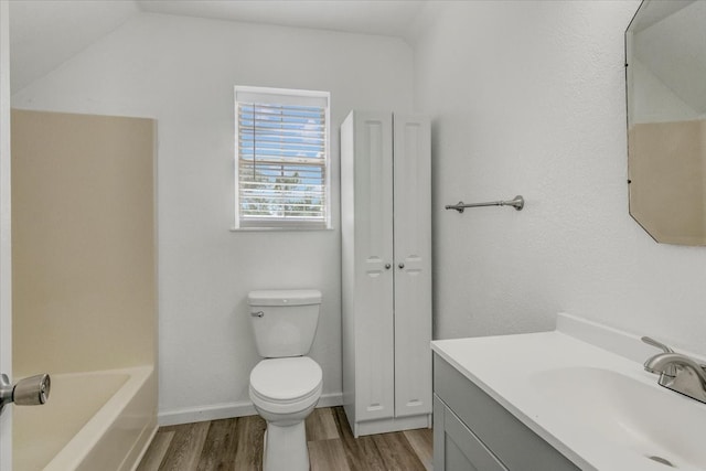 full bathroom with hardwood / wood-style flooring, toilet, vanity, and washtub / shower combination