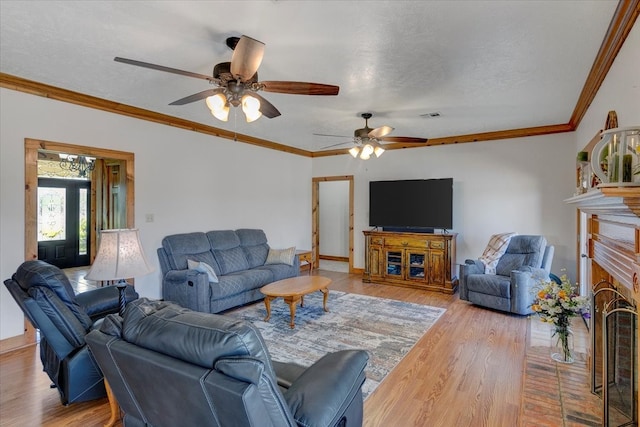 living room with ornamental molding, ceiling fan, hardwood / wood-style flooring, and a fireplace