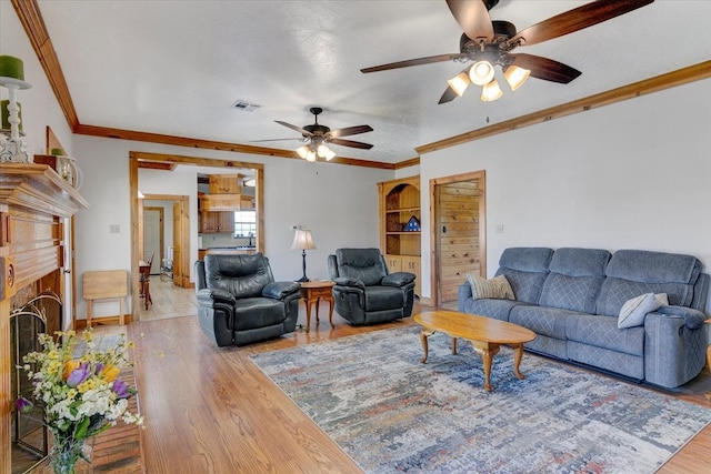 living room featuring hardwood / wood-style floors, ceiling fan, ornamental molding, and a fireplace