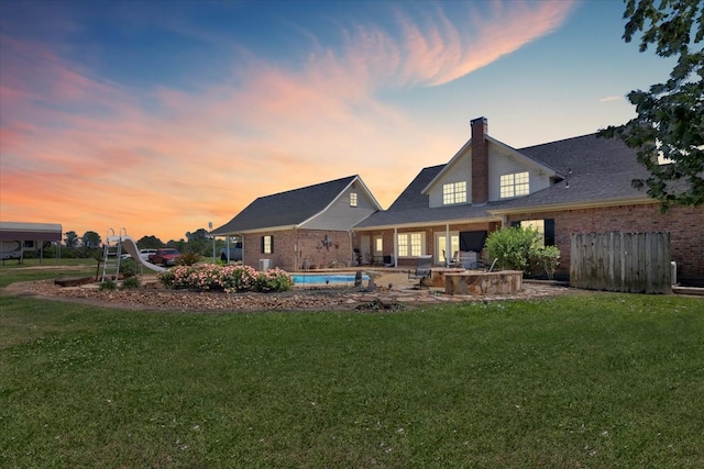 back house at dusk with a patio area and a yard