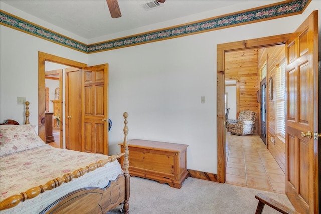 bedroom with wood walls, ceiling fan, and light tile floors