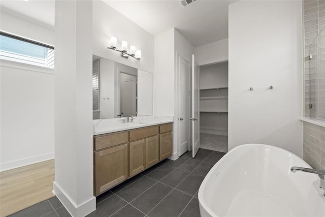 bathroom featuring a tub to relax in, vanity, tile patterned flooring, and a skylight