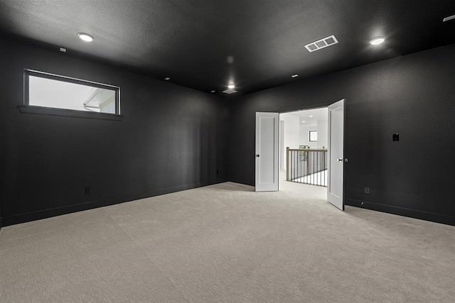 empty room with light carpet and a textured ceiling