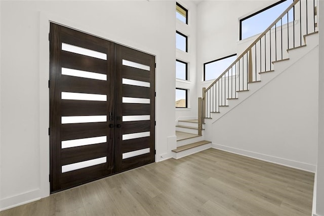 foyer entrance featuring a towering ceiling and light wood-type flooring