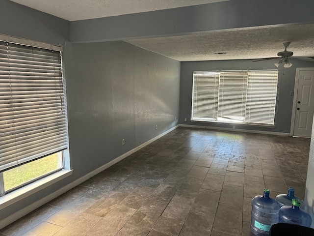 tiled empty room with ceiling fan and a textured ceiling