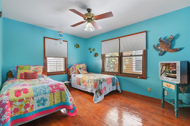 bedroom with multiple windows, ceiling fan, and dark hardwood / wood-style floors