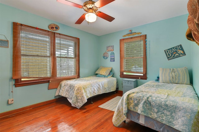 bedroom featuring ceiling fan, dark hardwood / wood-style flooring, and multiple windows