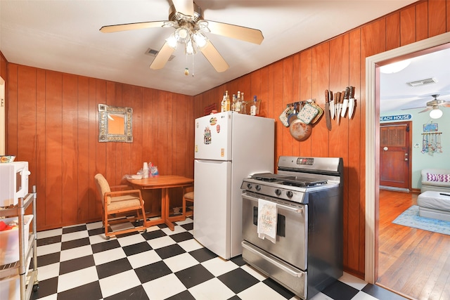 kitchen featuring light hardwood / wood-style flooring, white appliances, ceiling fan, and wooden walls