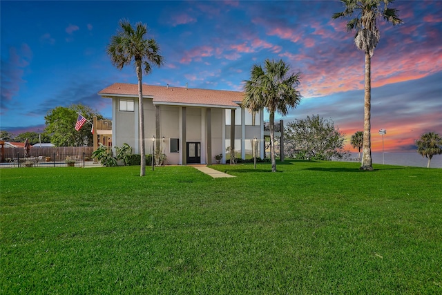 back of house featuring fence, a lawn, and stucco siding