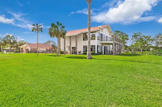 rear view of property featuring a lawn and a balcony