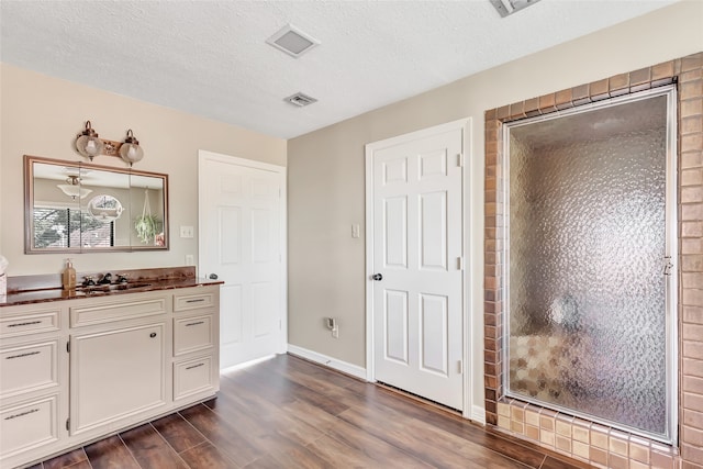 bathroom with a shower with shower door, wood-type flooring, a textured ceiling, and vanity