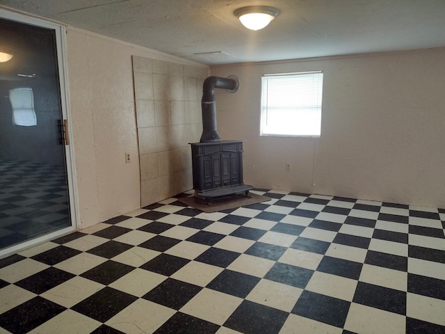 empty room with a wood stove and light tile patterned floors