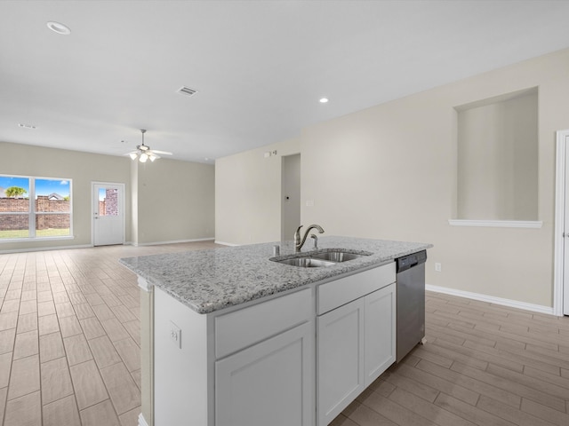 kitchen with an island with sink, stainless steel dishwasher, sink, white cabinetry, and ceiling fan