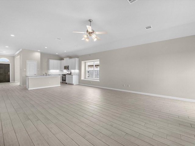 unfurnished living room with baseboards, light wood finished floors, a ceiling fan, and recessed lighting