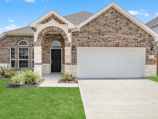 french country inspired facade with concrete driveway, a shingled roof, an attached garage, and brick siding