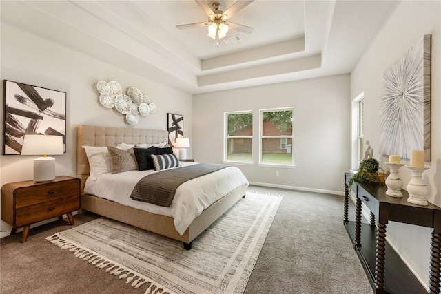 carpeted bedroom with ceiling fan and a raised ceiling