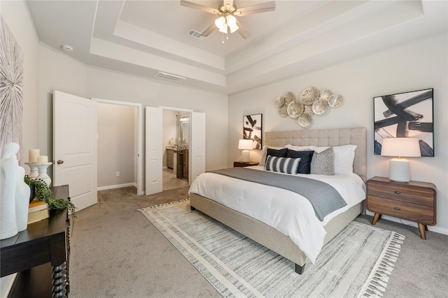 bedroom featuring ceiling fan, carpet, a tray ceiling, and connected bathroom