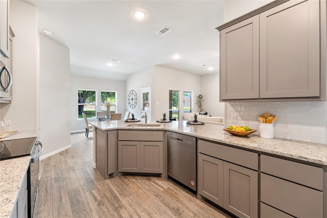 kitchen featuring gray cabinets, stainless steel dishwasher, stove, sink, and light stone countertops