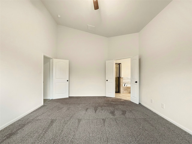 carpeted empty room with high vaulted ceiling and ceiling fan