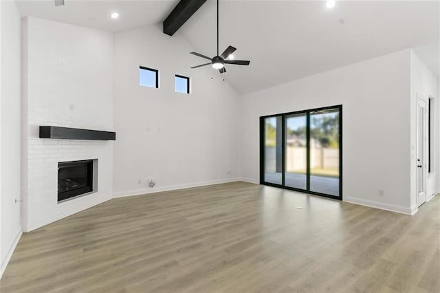 unfurnished living room featuring beam ceiling, ceiling fan, light hardwood / wood-style flooring, high vaulted ceiling, and a fireplace