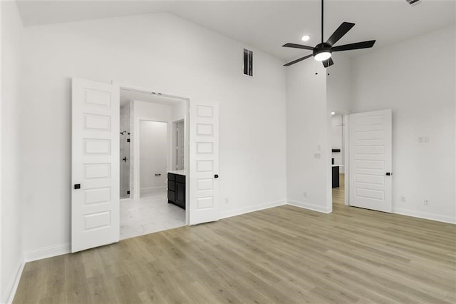 spare room with light wood-type flooring, high vaulted ceiling, and ceiling fan