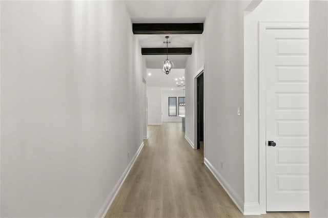 hall with beam ceiling, a chandelier, and light wood-type flooring