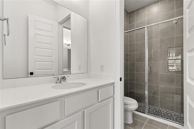 bathroom with tile patterned floors, vanity, toilet, and an enclosed shower