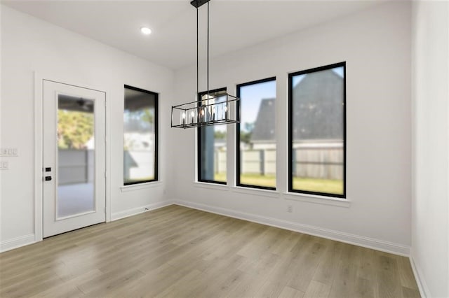 unfurnished dining area with an inviting chandelier and light hardwood / wood-style flooring