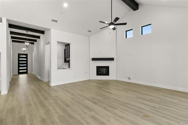 unfurnished living room with beam ceiling, a large fireplace, light hardwood / wood-style floors, and ceiling fan with notable chandelier