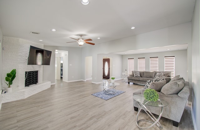 living room with ceiling fan, a fireplace, and light hardwood / wood-style floors