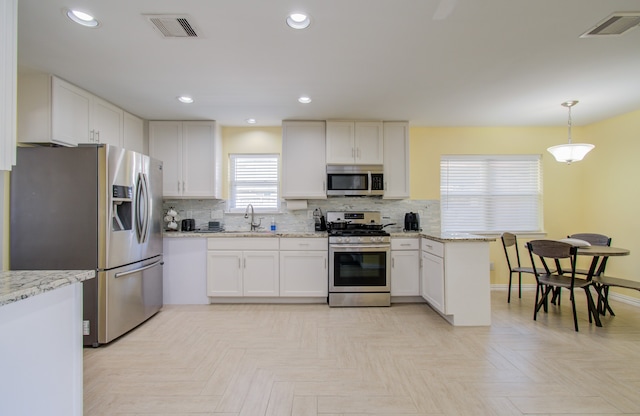 kitchen featuring white cabinetry, sink, decorative light fixtures, decorative backsplash, and appliances with stainless steel finishes