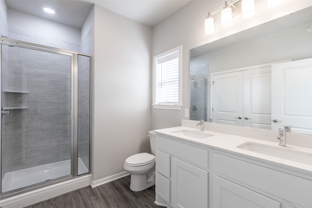 bathroom with a shower with shower door, toilet, hardwood / wood-style floors, and double sink vanity