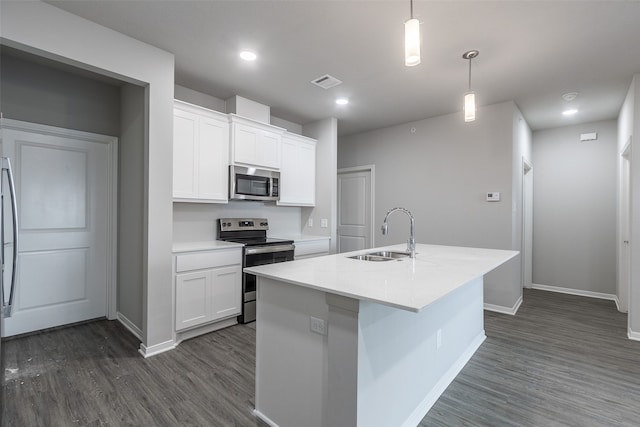 kitchen featuring appliances with stainless steel finishes, white cabinets, sink, dark wood-type flooring, and an island with sink