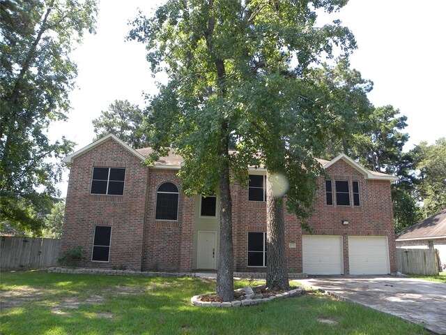 view of front of property with an attached garage, fence, concrete driveway, and brick siding