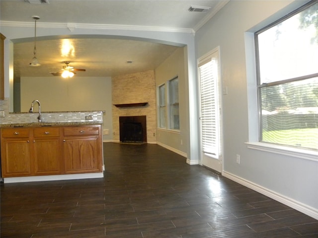 kitchen with tasteful backsplash, sink, a large fireplace, ceiling fan, and ornamental molding