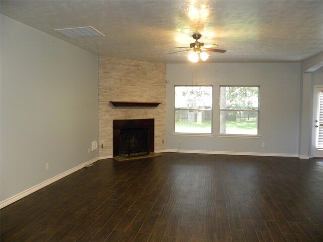 unfurnished living room with a fireplace, visible vents, dark wood-type flooring, a ceiling fan, and baseboards