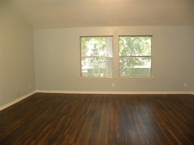 spare room featuring dark wood-style flooring and baseboards