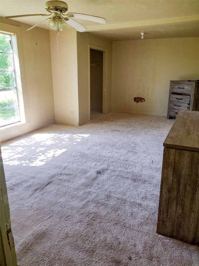 unfurnished bedroom featuring a closet, light colored carpet, multiple windows, and ceiling fan