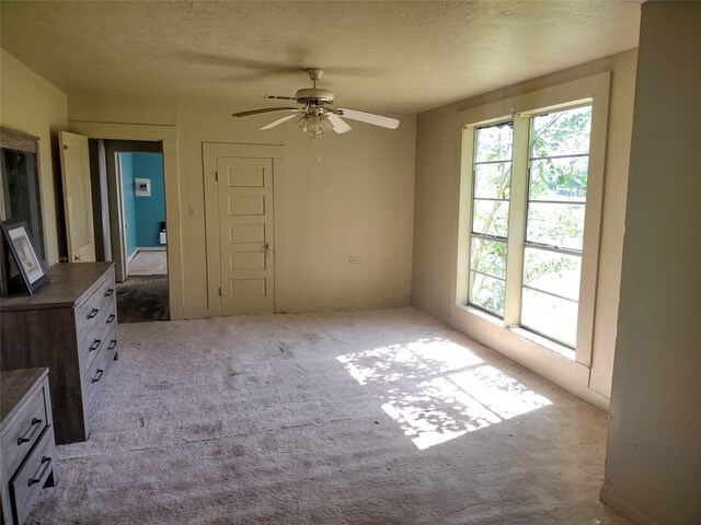 unfurnished bedroom with multiple windows, light carpet, and ceiling fan