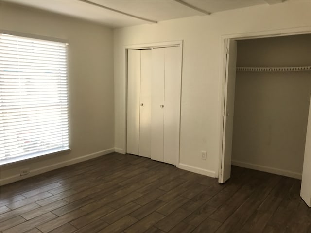 unfurnished bedroom with dark wood-type flooring and multiple windows