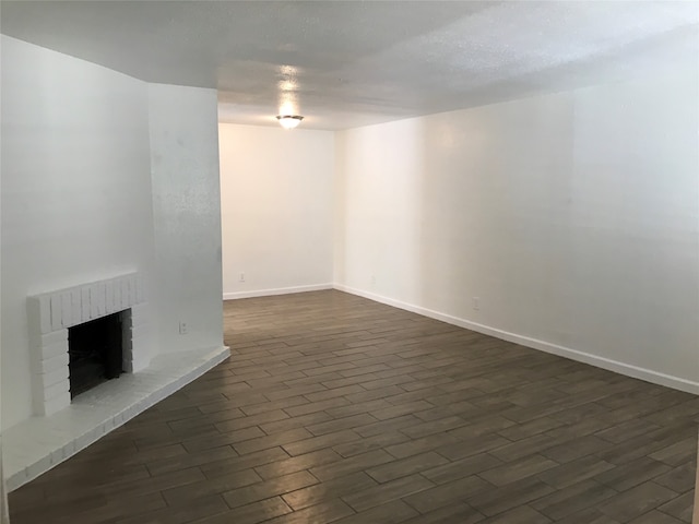 unfurnished living room with a brick fireplace and dark hardwood / wood-style floors