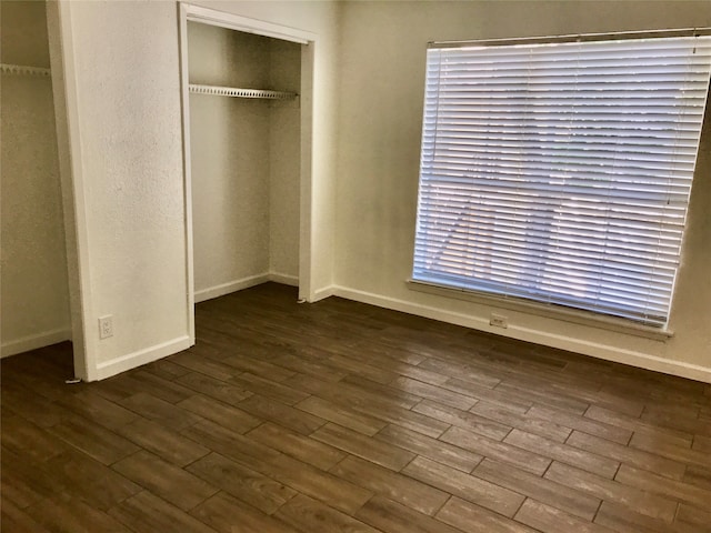 unfurnished bedroom featuring a closet and dark wood-type flooring