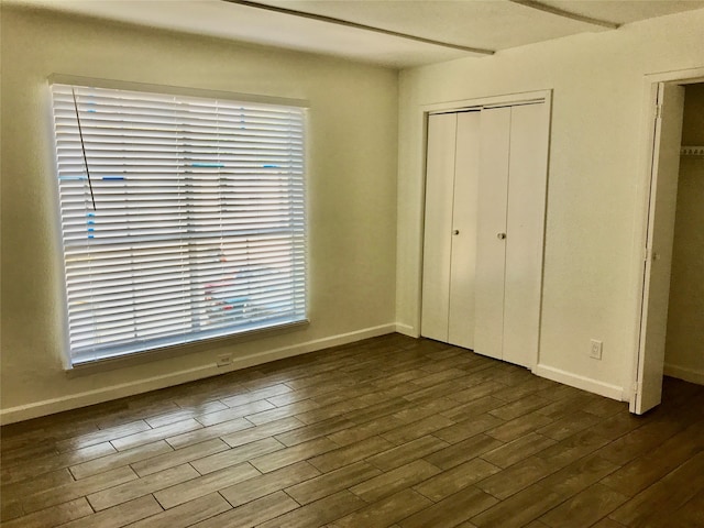 unfurnished bedroom with a closet and dark hardwood / wood-style floors