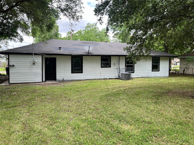 rear view of property featuring central AC unit and a lawn