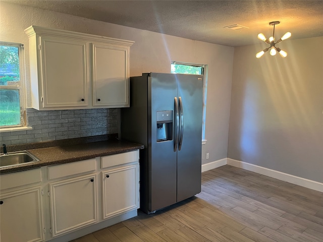 kitchen featuring stainless steel fridge with ice dispenser, light hardwood / wood-style flooring, tasteful backsplash, white cabinets, and a chandelier