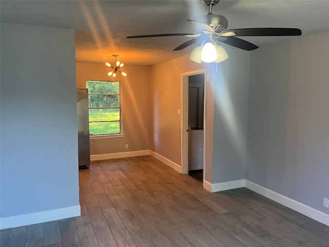 spare room featuring ceiling fan with notable chandelier and dark hardwood / wood-style floors