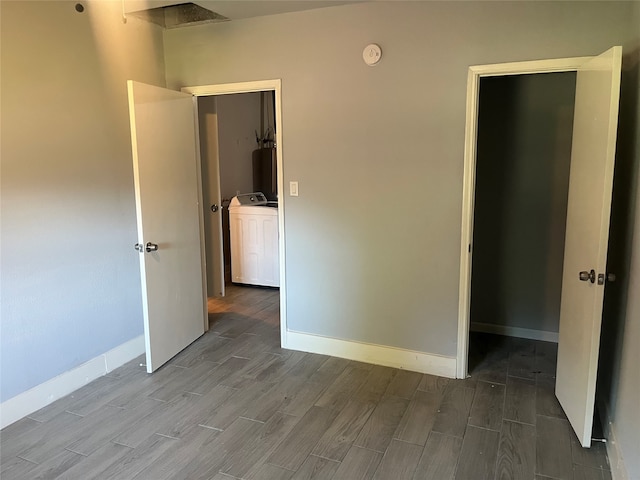 unfurnished bedroom featuring a closet, a spacious closet, hardwood / wood-style floors, and washer and dryer